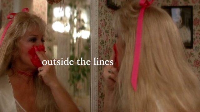 Diane Ladd looking in a mirror in Wild at hear while smearing red lipstick all over her face. White text reads: outside the lines