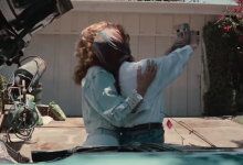 Thelma and Louise posing for a Polaroid camera outside a house in front of a car from the back
