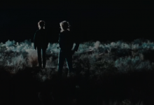 Thelma and Louise standing in the moonlight with their backs facing us