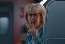A white woman with blonde hair and glasses shushing someone